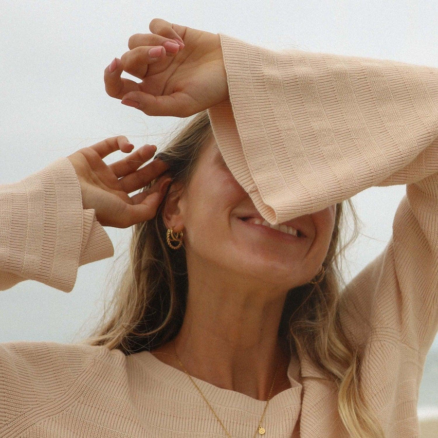 Woman with beige jumper wearing gold hoop earrings and gold necklace - womens jewellery by Australian waterproof jewellery brands indie and harper