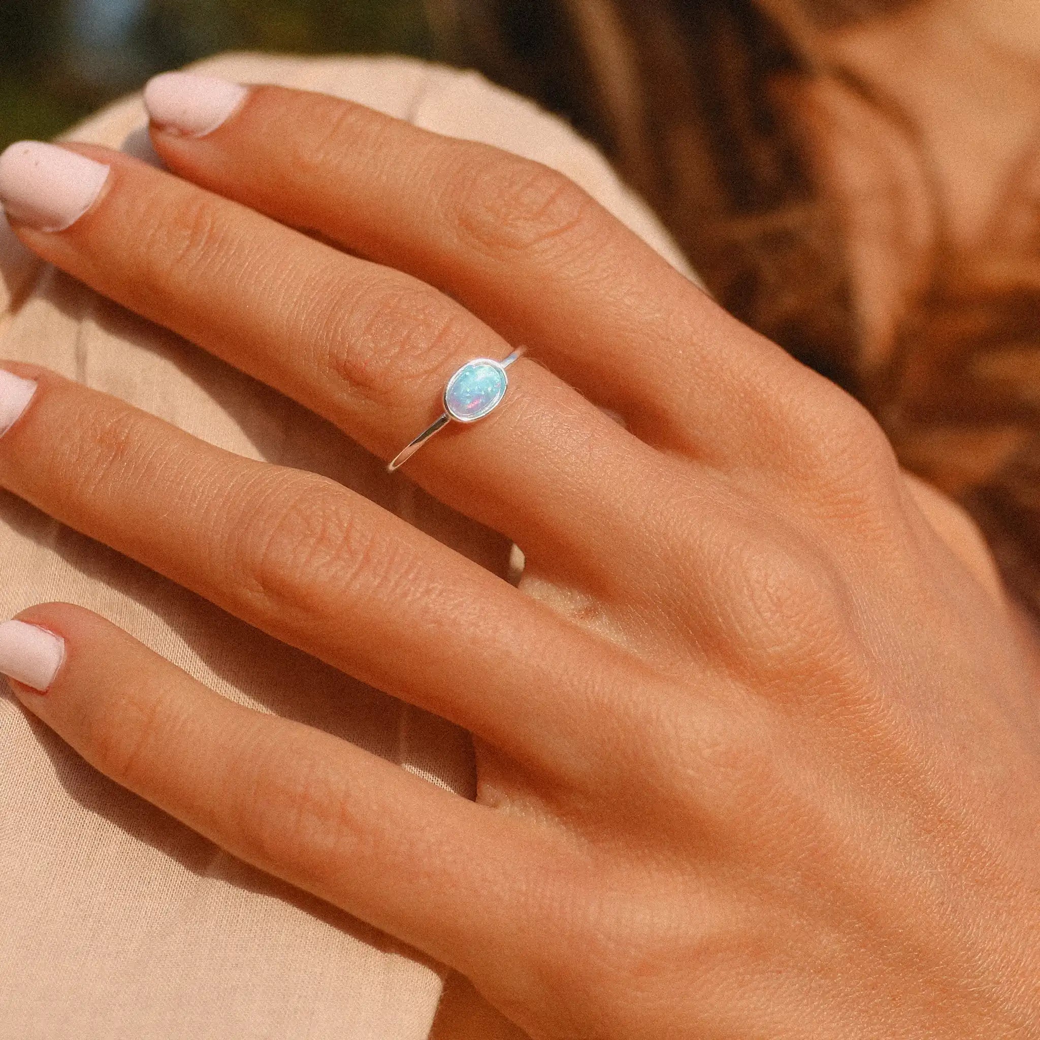 woman wearing a sterling silver dainty blue opal ring - opal jewellery by womens jewelry brand indie and harper