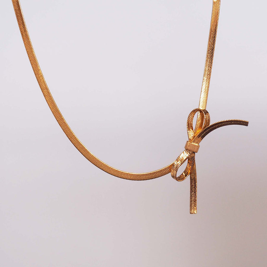 dainty bow choker necklace - this stainless steel necklace has 18k gold plating with a dainty bow design made out of a snake chain - women's dainty jewellery by online jewellery brand indie and harper