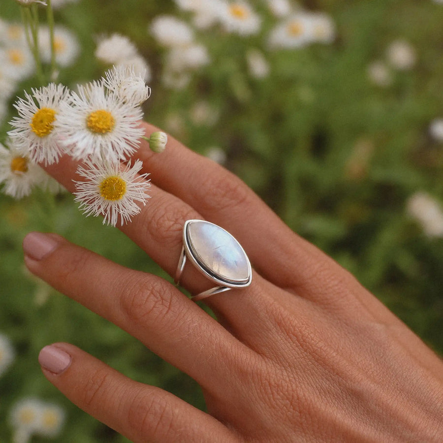 Woman's hand holding flowers and wearing a large silver moonstone ring - moonstone jewellery by Australian jewellery brands indie and Harper 