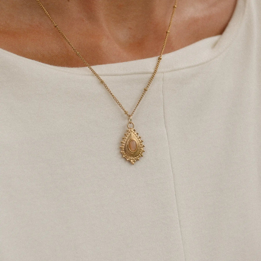 woman in a white dress wearing a stainless steel necklace plated in 18k gold with a natural stone - bohemian jewellery online