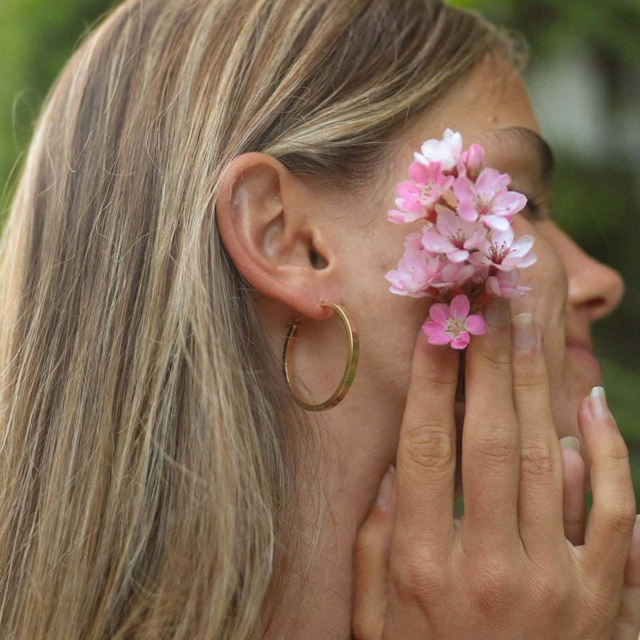 Woman wearing gold hoop Earrings - gold jewellery by waterproof jewellery brands indie and Harper