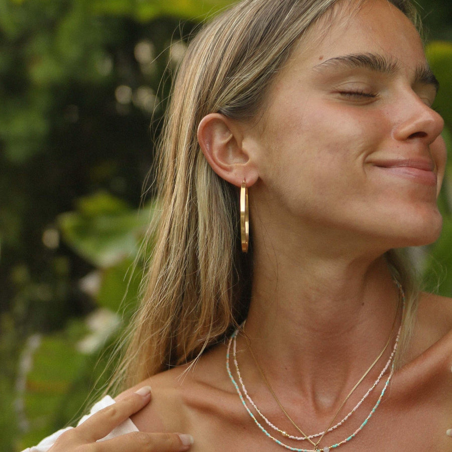 Woman wearing gold hoop Earrings and beaded necklaces - by Australian jewellery brand indie and harper