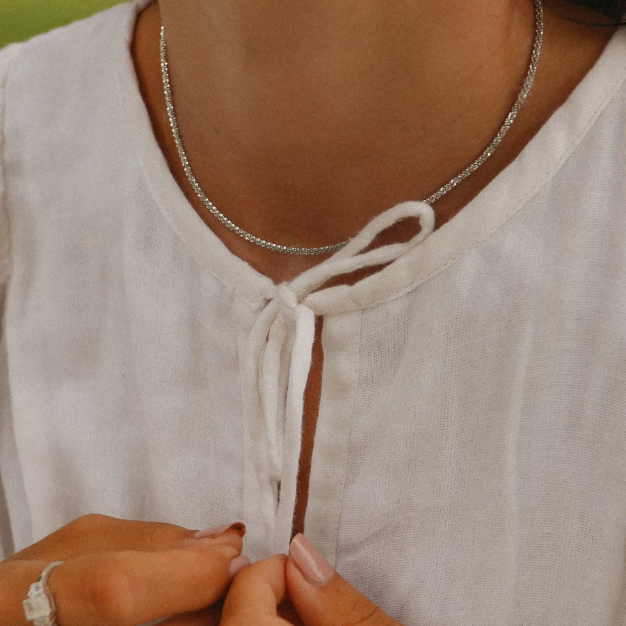 woman in a white top wearing a sterling silver choker necklace plated in white gold - women's sterling silver jewelry online