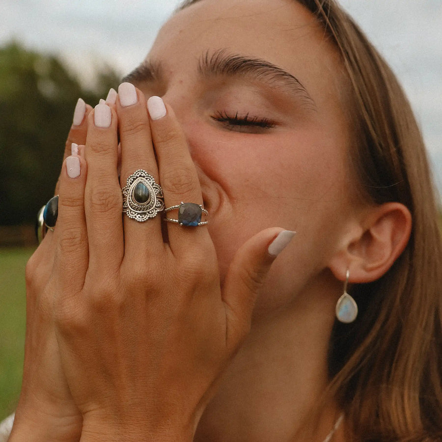 woman with her hands over her face wearing two sterling silver labradorite rings - boho jewellery by australian jewellery brands indie and harper