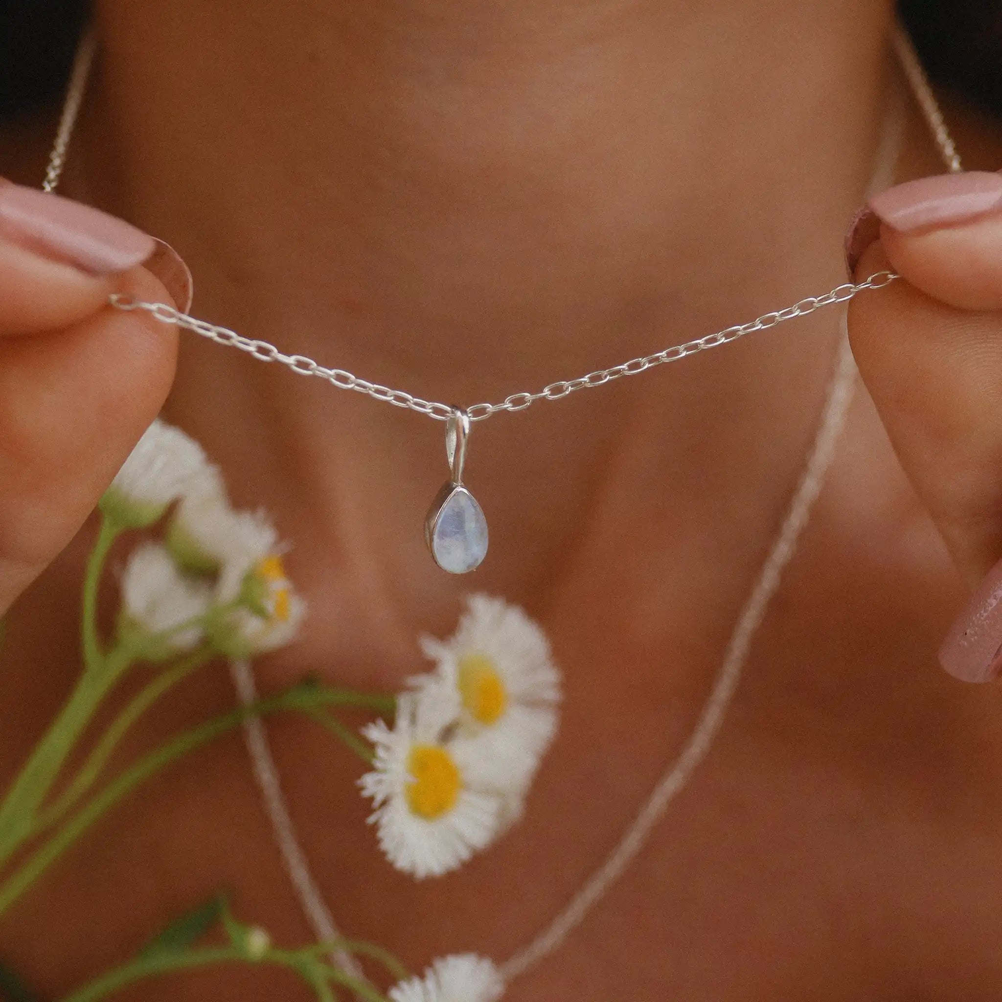 Woman holding up small teardrop shaped sterling silver moonstone necklace - moonstone jewellery by online Australian jewellery brand indie and Harper 