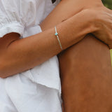 Woman sitting down wearing a white top and sterling silver Navajo hand carved turquoise bracelet - Native American Jewelry - turquoise jewellery by online jewellery brand indie and Harper 