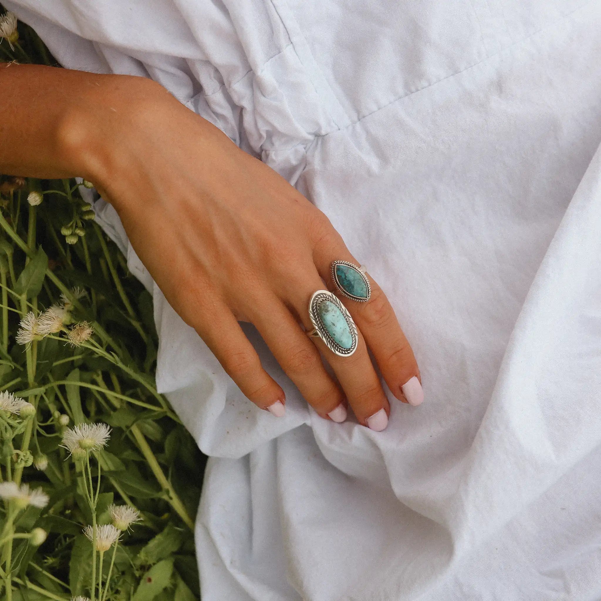 woman laying in a field of daisies wearing a white dress and two sterling silver turquoise rings - turquoise jewellery by Australian jewellery brands online indie and harper