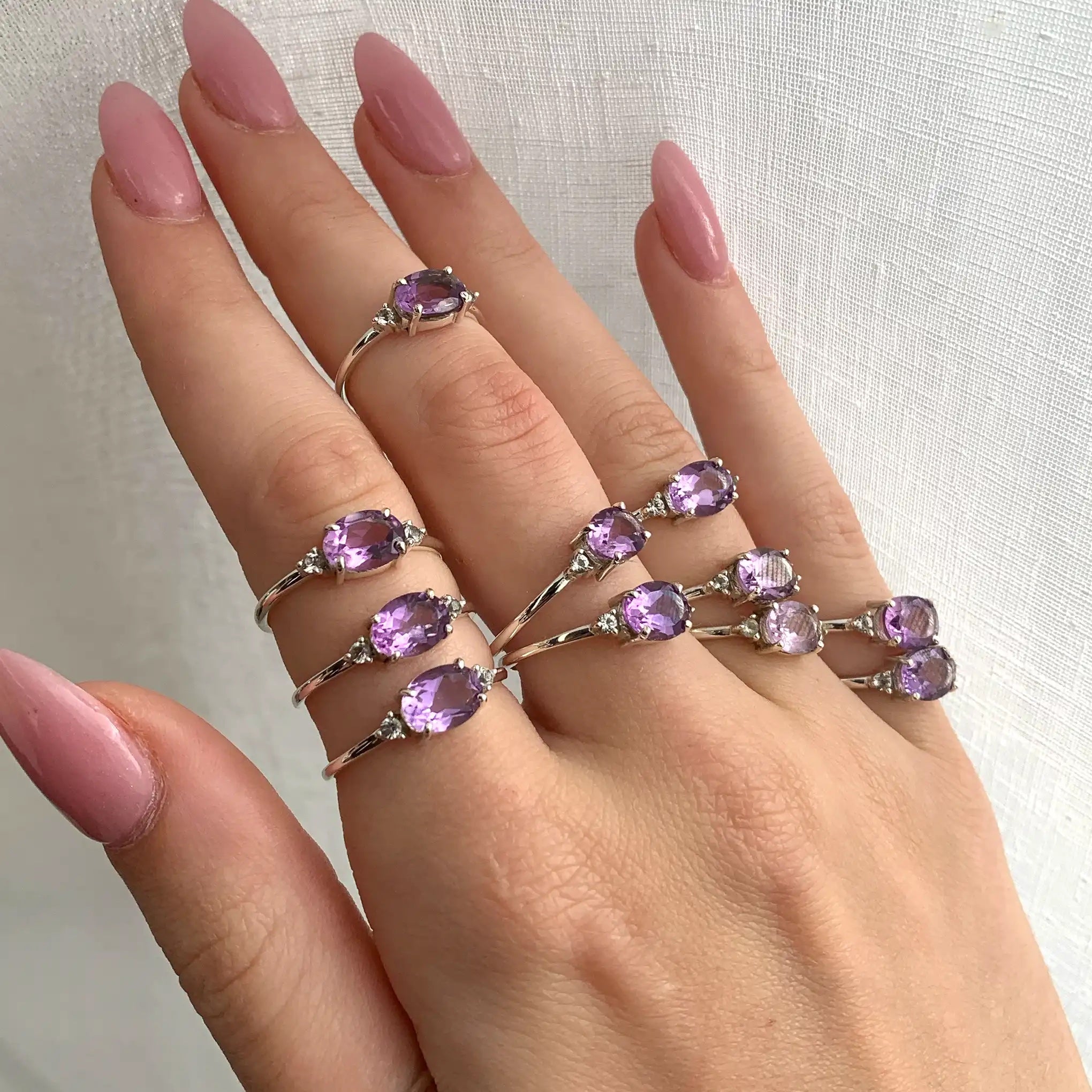 Hand wearing multiple white topaz and pink amethyst rings - white topaz and amethyst jewellery by australian jewellery brands indie and harper