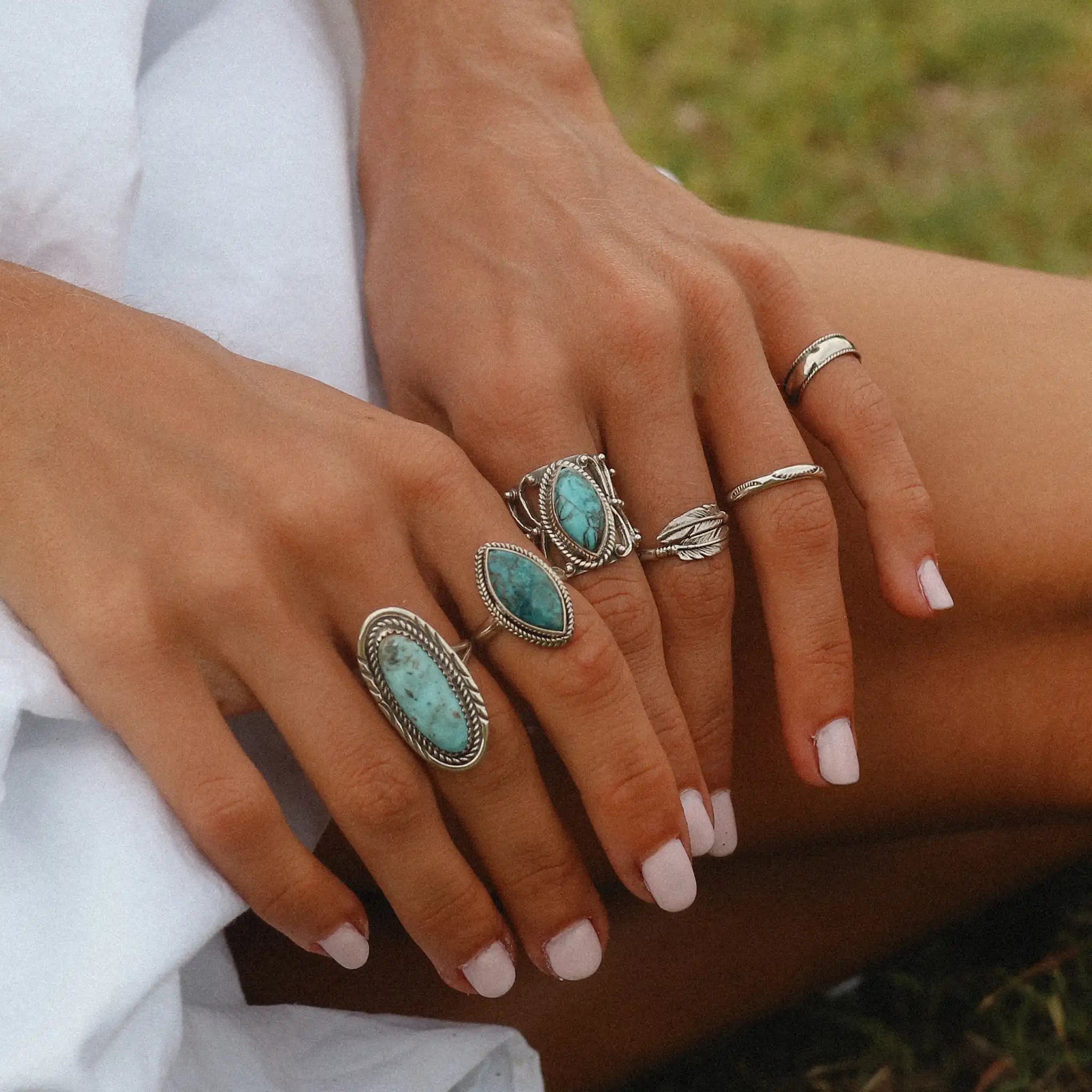 Woman's hands wearing sterling silver turquoise rings - turquoise jewellery by womens gemstone jewellery brand indie and harper