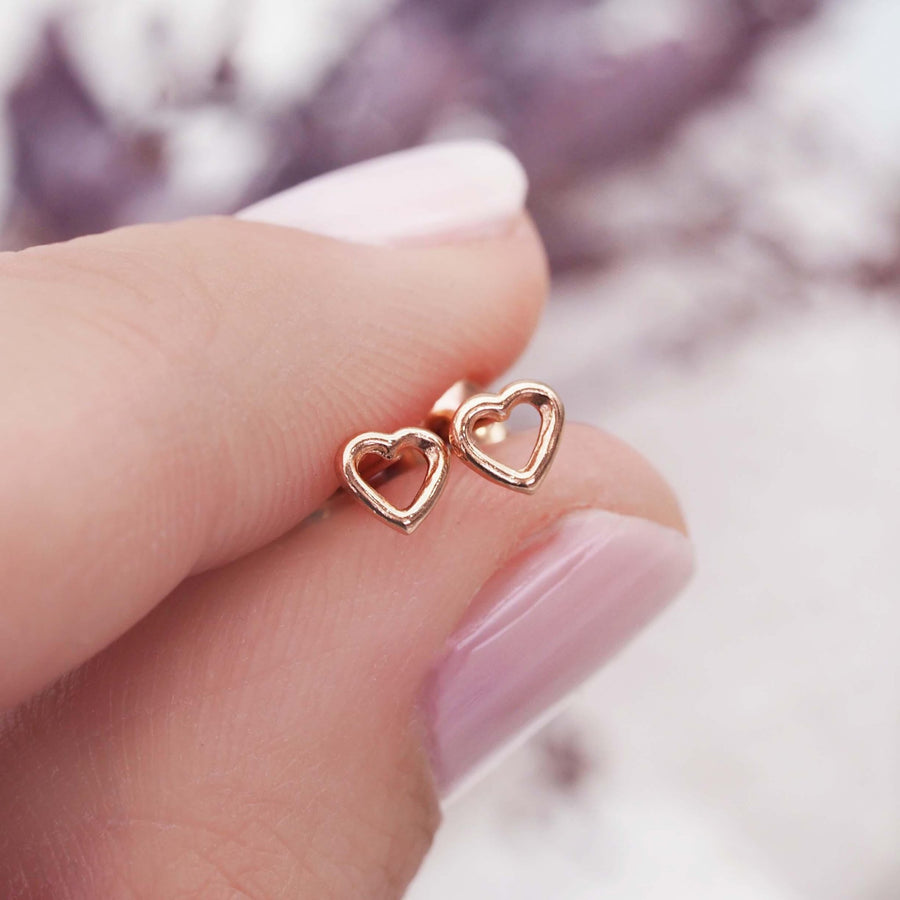 Fingers holding Dainty heart shaped Rose Gold Earrings - rose gold jewellery by Australian jewellery brands online indie and harper