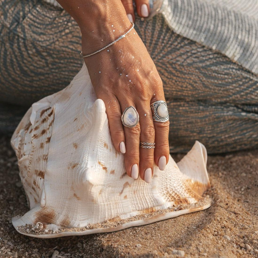 woman holding large shell on the beach and wearing sterling silver moonstone rings - womens boho jewellery by australian jewellery brands online indie and harper