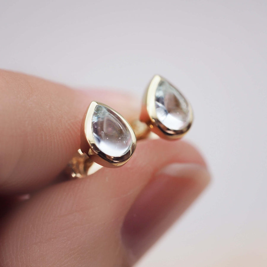 Fingers holding pair of November Birthstone Earrings - gold blue topaz earrings - womens jewellery by Australian jewellery brands online indie and harper