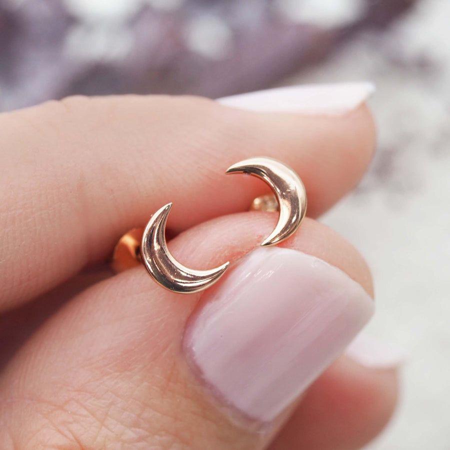 Fingers holding Dainty Rose Gold Earrings in dainty crescent moon shape - womens rose gold jewellery Australia by Australian jewellery brands indie and harper