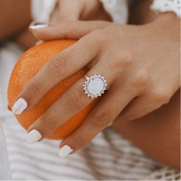 Woman holding an orange and wearing a silver Moonstone Ring - moonstone jewelry by womens jewelry online brand indie and harper 